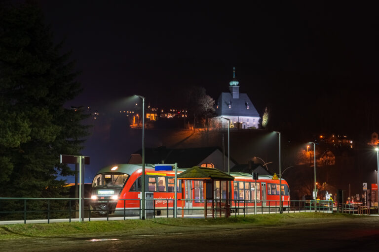 Olbernhau-Gruenthal im Advent - Zug vor beleuchteter Kirche bei Nacht.